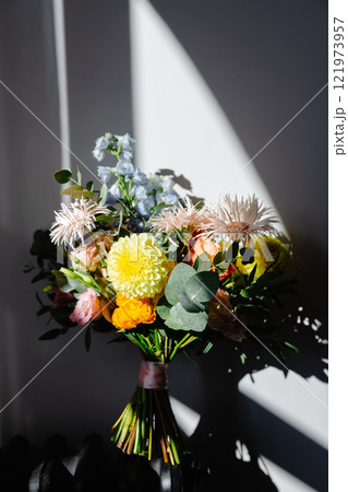 Colorful bridal bouquet resting on a chair, illuminated by window light 121973957