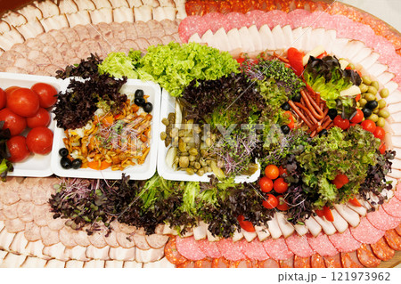 Catering platter with sliced meat, vegetables, mushrooms and olives decorating a festive table 121973962