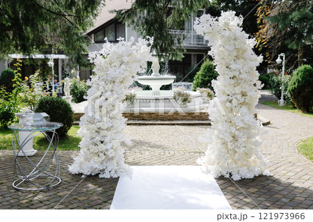 White floral arrangement creating beautiful wedding arch in garden White floral arrangement creating beautiful wedding arch in garden 121973966