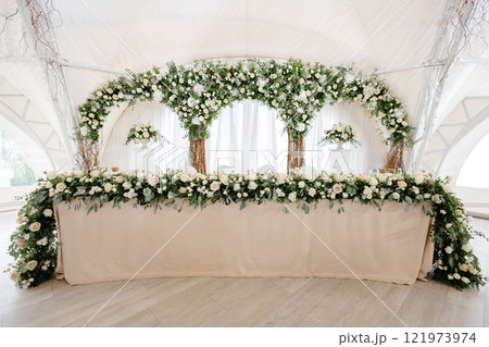 Elegant wedding reception hall featuring round tables, white and gold chairs, and floral arrangements Elegant wedding reception hall featuring round tables, white and gold chairs, and floral arrangements 121973974