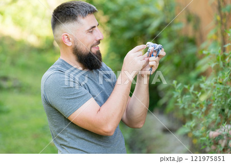 Man gently holds a small bird outdoors, enjoying a peaceful moment in nature. 121975851