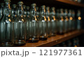 Glass bottles arranged neatly on a wooden shelf in a dimly lit storage area during early evening hours 121977361