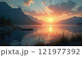 Sunset reflecting over a tranquil lake surrounded by mountains and trees 121977392