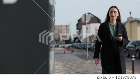 Woman receiving parcel from post terminal machine using smartphone outdoors. Parcel delivery machine. Mail delivery and post service, online shopping, e commerce concept. 121978078