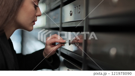 Close up beautiful woman unlocking mailbox and taking mail in apartment building. Close up beautiful woman unlocking mailbox and taking mail in apartment building. 121978090