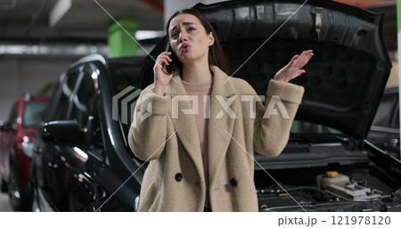 Young desperate woman calling emergency help near broken car in the parking lot. 121978120
