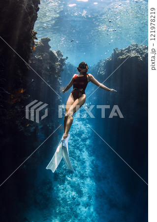 Free diver posing underwater under reef rocks in blue ocean on Menjangan. 121978219