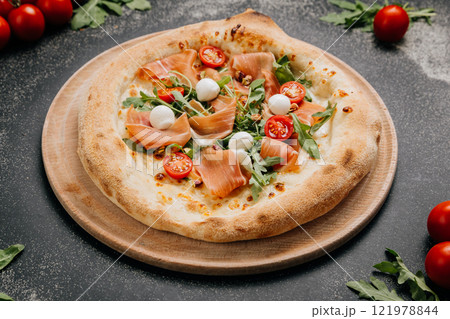 Gourmet pizza with prosciutto, mozzarella, arugula, and cherry tomatoes, food lover's feast 121978844