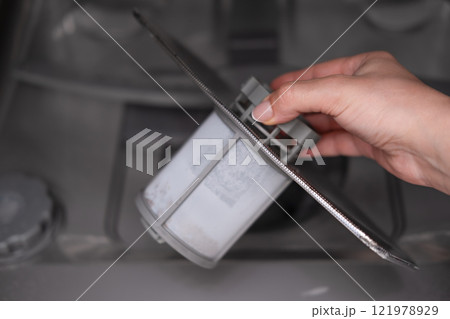 woman's hand checking the filter in the dishwasher 121978929