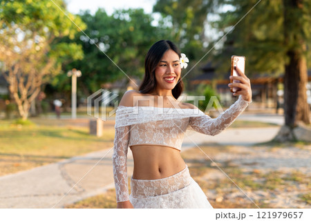 Beautiful woman smiling and taking selfie in a park Beautiful woman smiling and taking selfie in a park 121979657
