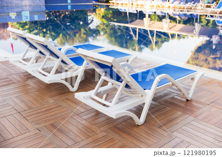 Vacant sun loungers are located by the pool in a resort hotel 121980195