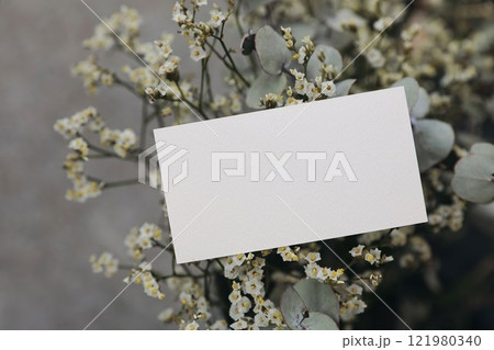 Floral wedding, birthday mockup. Blank textured paper business card, invitation. White limonium flowers and eucalyptus tree branches bouquet. Blurred background. Floristry concept. Gift note. Floral wedding, birthday mockup. Blank textured paper business card, invitation. White limonium flowers and eucalyptus tree branches bouquet. Blurred background. Floristry concept. Gift note. 121980340