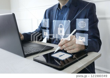 Man in suit working on laptop, digital tablet. Cyber security shield, lock. Glowing icons of computer alerts, folders. Protection of sensitive data, digital environment against hacker attacks threats. 121980349