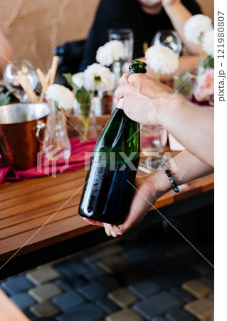 Uncorking a chilled champagne bottle at an elegant celebration, surrounded by floral decor 121980807