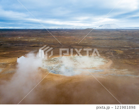 Steam billows from the geothermal area of Hverir near the Kafla vulcanic area of Iceland, highlighting vibrant mineral deposits in the foreground against a striking landscape 121981898