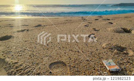 Garbage, plastic, and wastes on the beach of Portugal. Sand beaches polluted with pieces of plastic, cigarette pack 121982123