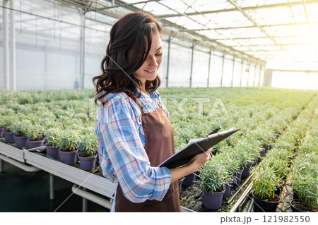 Glasshouse supervisor checking the plants and making notes 121982550
