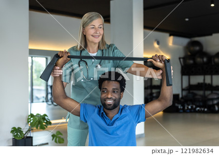 Young african american man exercising with a stretch band during rehabilitation session 121982634