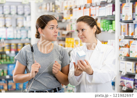 Woman pharmacist helping woman customer to choose remedy in pharmacy Woman pharmacist helping woman customer to choose remedy in pharmacy 121982697