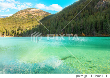 Mountain lake with emerald waters surrounded with forests in fall. 121984101