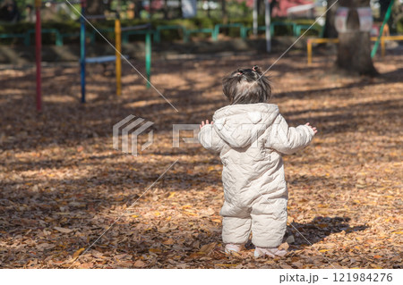 【落ち葉で敷き詰められた冬の公園で遊ぶ1歳児 立つ後ろ姿】 【落ち葉で敷き詰められた冬の公園で遊ぶ1歳児 立つ後ろ姿】 121984276