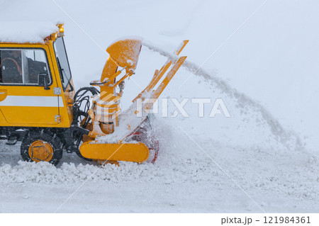 雪道の道路を除雪する小型のロータリー除雪車 121984361
