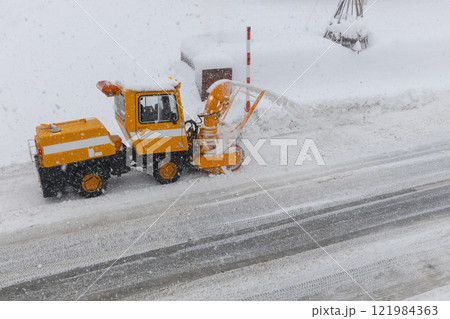 雪道の道路を除雪する小型のロータリー除雪車 121984363