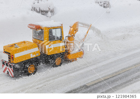雪道の道路を除雪する小型のロータリー除雪車 121984365
