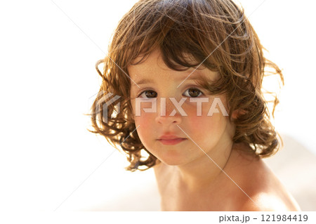 Close-up portrait of a cute toddler girl on the sunny beach. Close-up portrait of a cute toddler girl on the sunny beach. 121984419
