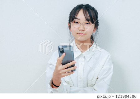 スマホを片手にカメラ目線で微笑む女性 スマホを片手にカメラ目線で微笑む女性 121984586