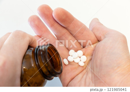 白い錠剤を手に取る 白い錠剤を手に取る 121985041