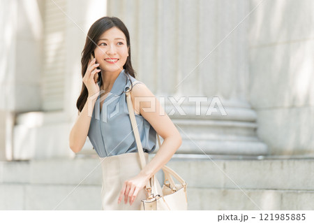 オフィス街でスマホで電話するビジネスウーマン オフィス街でスマホで電話するビジネスウーマン 121985885