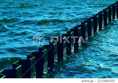 青い月夜に照らされるさざ波だった海面と港湾の錆びた古い鋼矢板の風景（レタッチ＆色彩加工素材） 121986305
