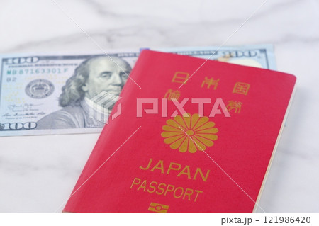 日本のパスポートと、アメリカ合衆国ドル（US＄）の100ドル紙幣で、海外旅行を計画しているイメージ 121986420