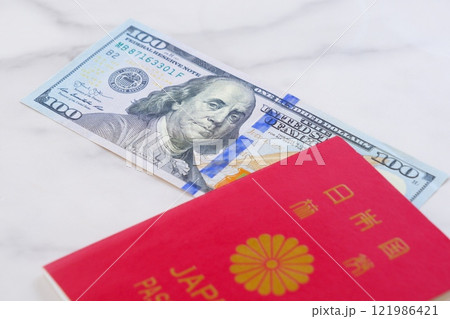 日本のパスポートと、アメリカ合衆国ドル（US＄）の100ドル紙幣で、海外旅行を計画しているイメージ 121986421