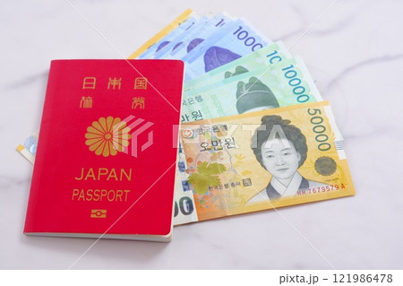 韓国の通貨、ウォンKRWの紙幣と、パスポート（一般旅券10年用赤色）で、韓国旅行のイメージ 121986478