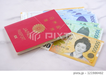 韓国の通貨、ウォンKRWの紙幣と、パスポート(一般旅券10年用赤色)で、韓国旅行のイメージ 韓国の通貨、ウォンKRWの紙幣と、パスポート(一般旅券10年用赤色)で、韓国旅行のイメージ 121986482