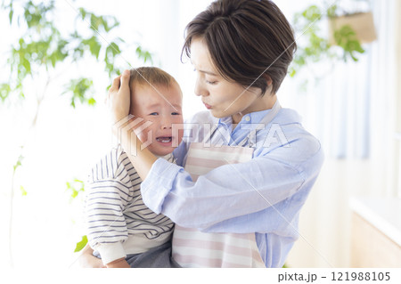 泣いている赤ちゃんをあやすママ 泣いている赤ちゃんをあやすママ 121988105