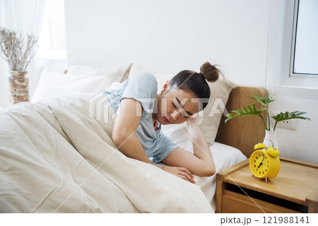 Asian women sleep wake up in white cozy bedroom happy time morning sunrise. Beautiful chinese use hand stop time alarm clock. Happy person lifestyle wake up in morning wellbeing relax sleepy napping 121988141