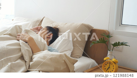 Asian women sleep wake up in white cozy bedroom happy time morning sunrise. Beautiful chinese use hand stop time alarm clock. Happy person lifestyle wake up in morning wellbeing relax sleepy napping 121988148