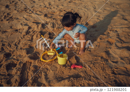 happy toddler baby girl playing sand toy on sea beach in Pattaya, Thailand 121988201