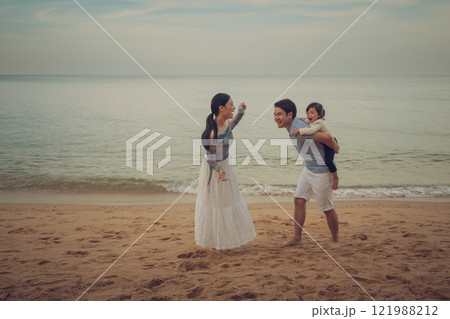 toddler baby girl with parent for piggyback and playing on sea beach in Pattaya, Thailand. happy family concept 121988212