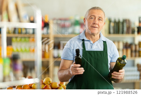 Mature salesman is offering olive oil in grocery store 121988526