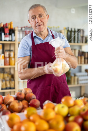 Mature salesman giving apples in grocery store Mature salesman giving apples in grocery store 121988577
