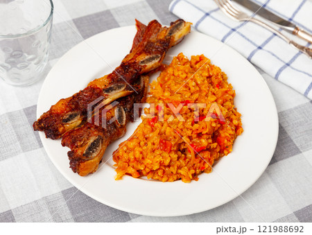 Delicious churrasco style grilled veal ribs served on plate with stewed cabbage with pearl barley porridge. Spain dish 121988692