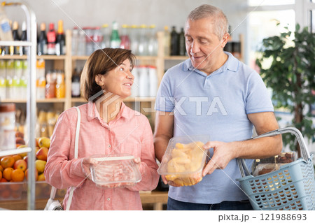 Mature spouses in store took raw chicken and pork meat from shelf, choose meat Mature spouses in store took raw chicken and pork meat from shelf, choose meat 121988693
