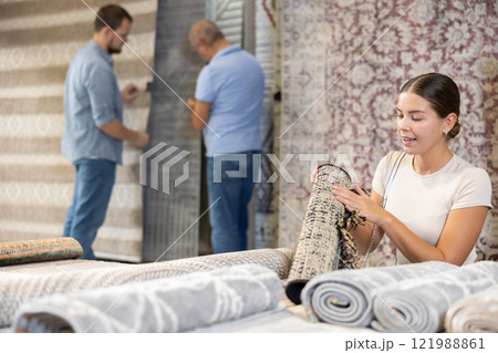 Young woman choosing carpet in building store 121988861