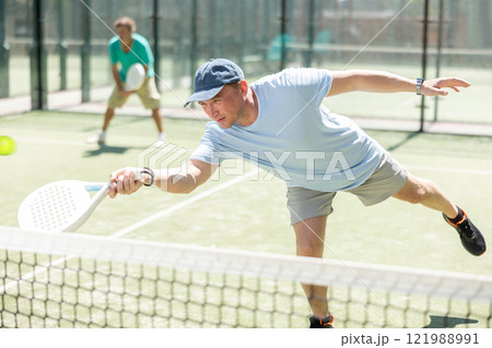 Two adult men playing doubles padel 121988991