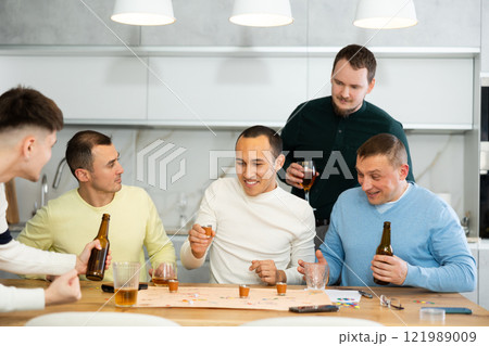 Cheerful men playing drinking board game at bachelor gathering 121989009