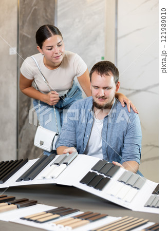 Couple clients touches and feels product, chooses fabric for curtains 121989010